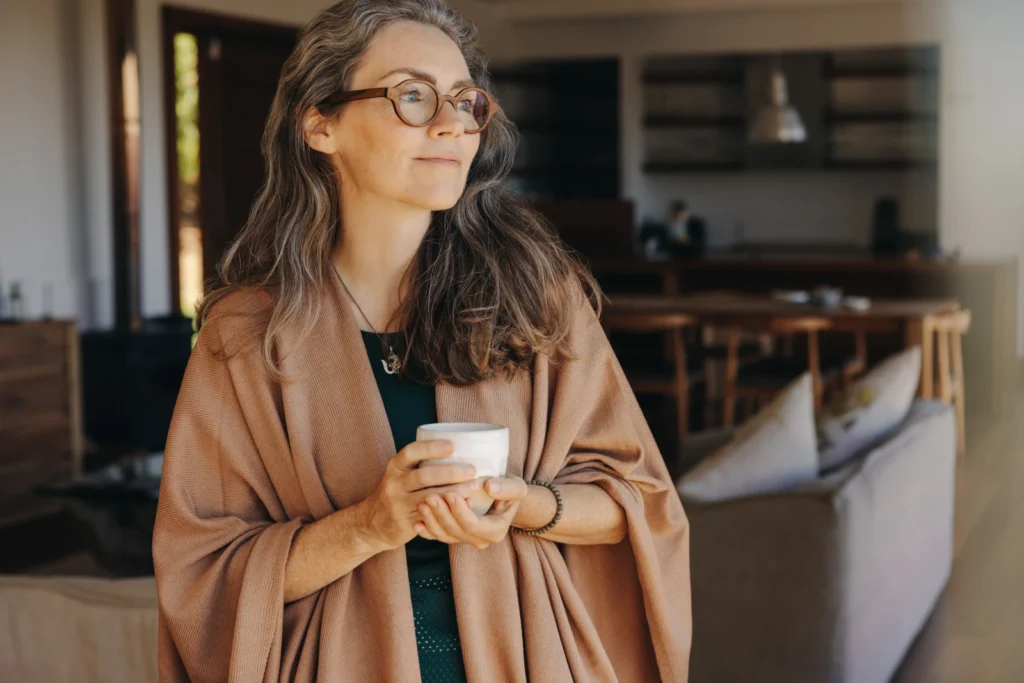 Donna con una tazza di caffè che guarda in lontananza.